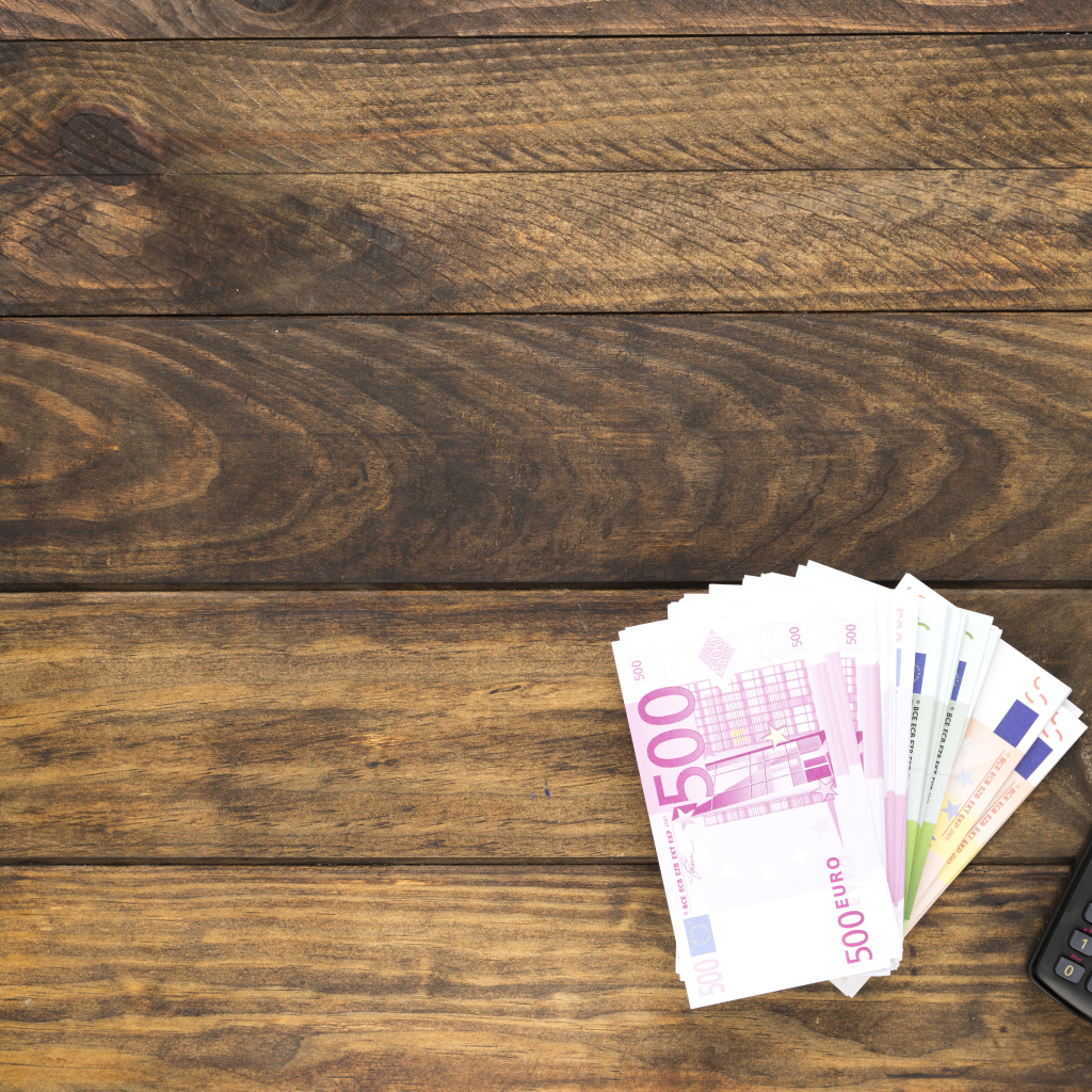 Купюры и калькулятор на деревянном фоне