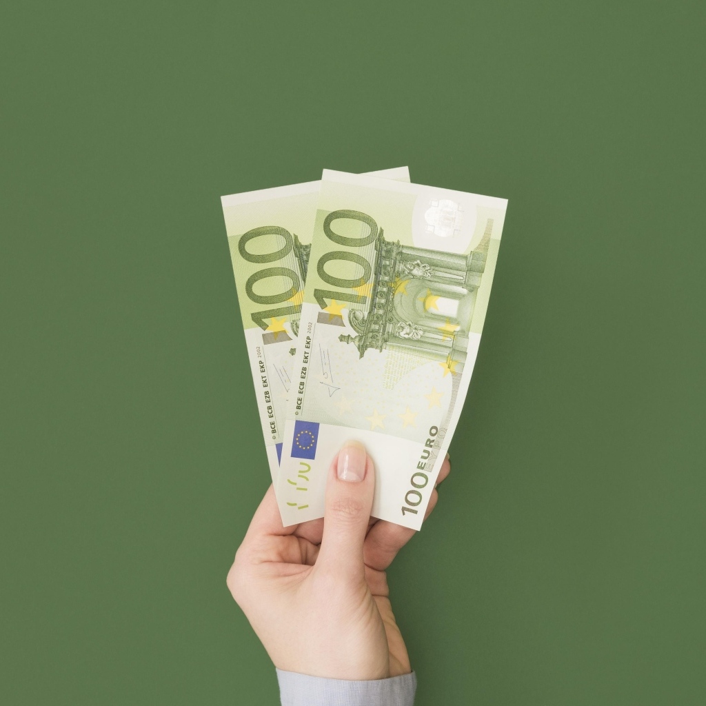 Две купюры по сто евро на зеленом фоне