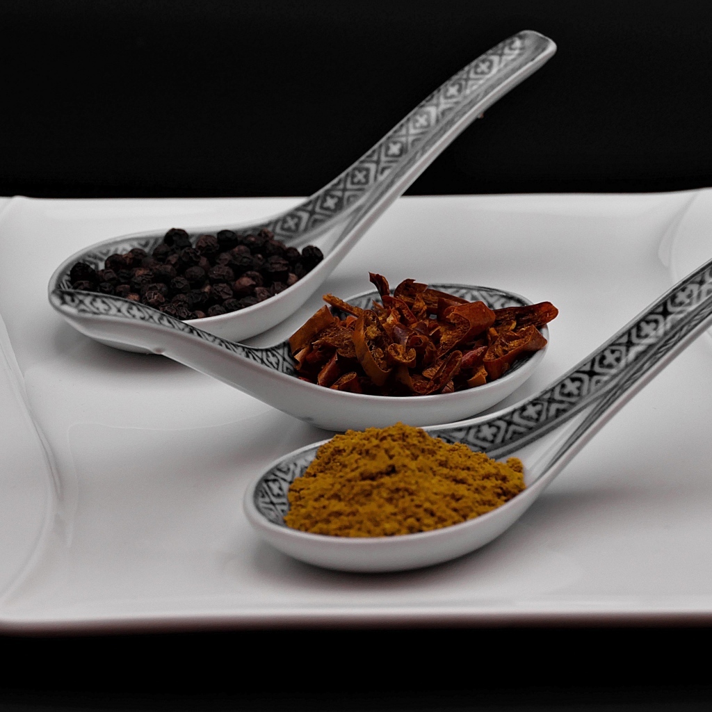 Ароматные специи в ложках на белой тарелке