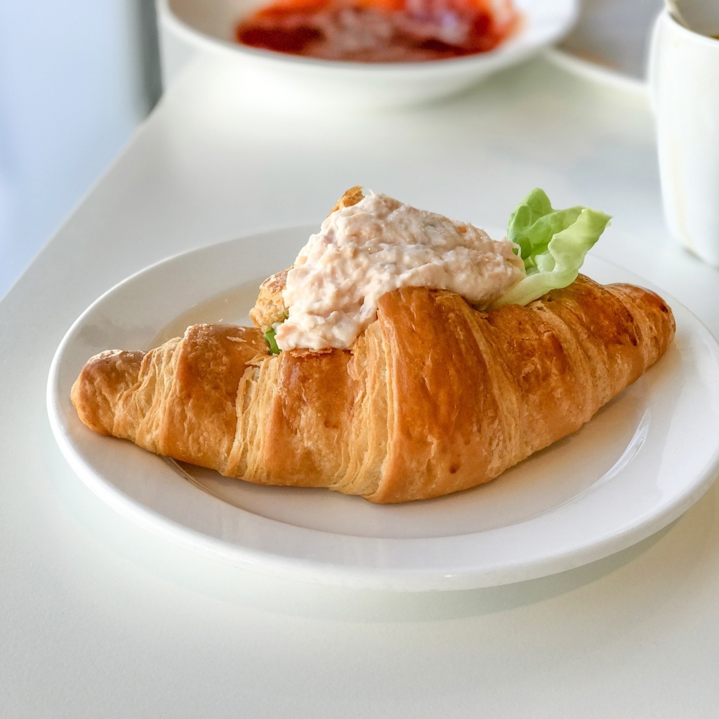 Круассан с начинкой на белой тарелке на завтрак 