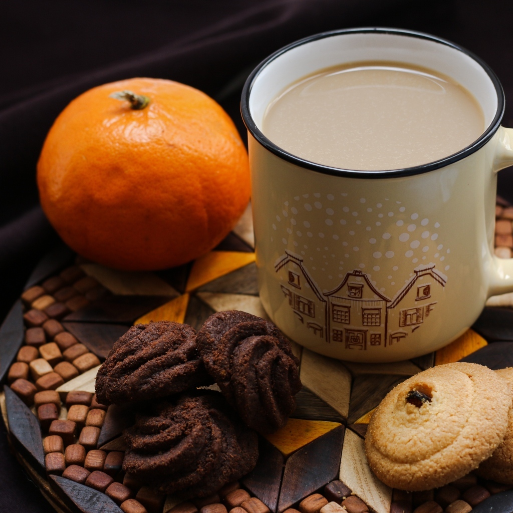 Чашка какао на тарелке с мандарином и печеньем