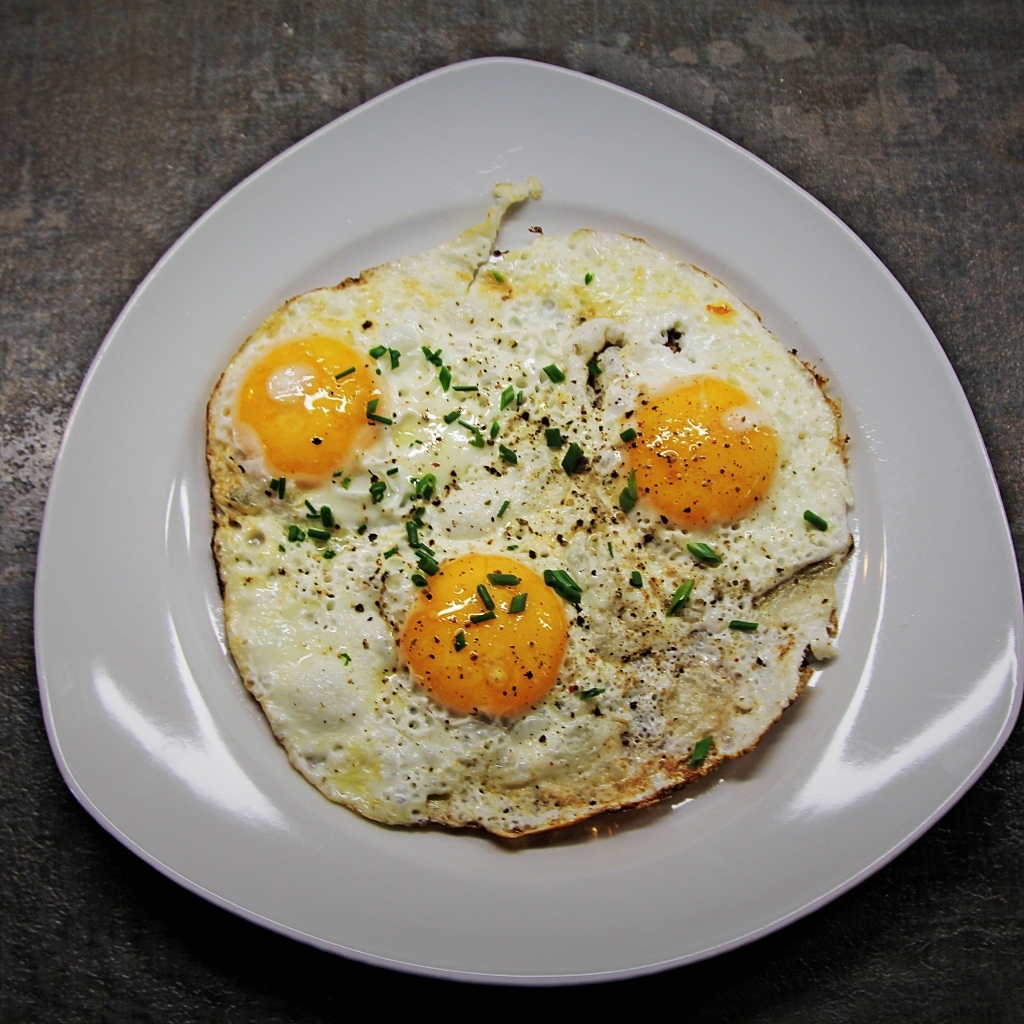 Яичница глазунья в тарелке на сером столе
