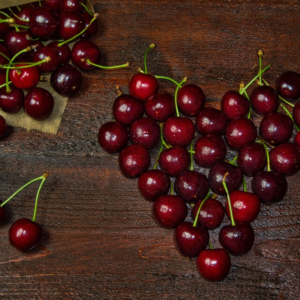 Сердце из спелых ягод черешни на деревянном столе