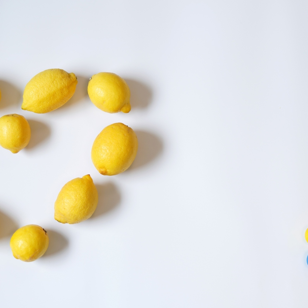 Сердце из желтых лимонов на сером фоне с конфетами