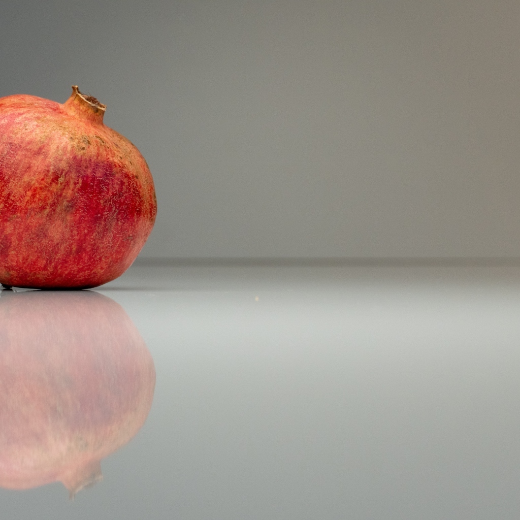 Красный гранат отражается в поверхности на сером фоне