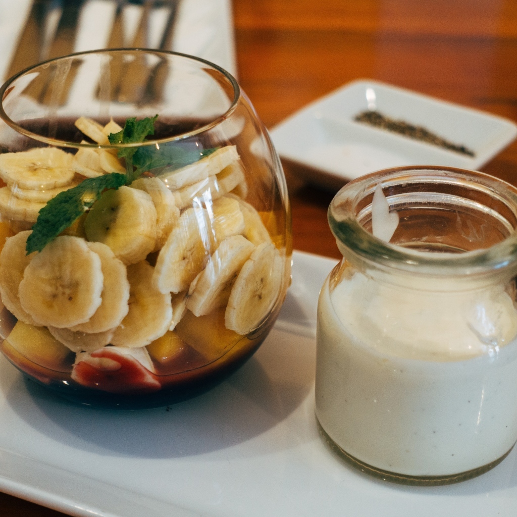 Нарезанные бананы в стакане на столе с йогуртом