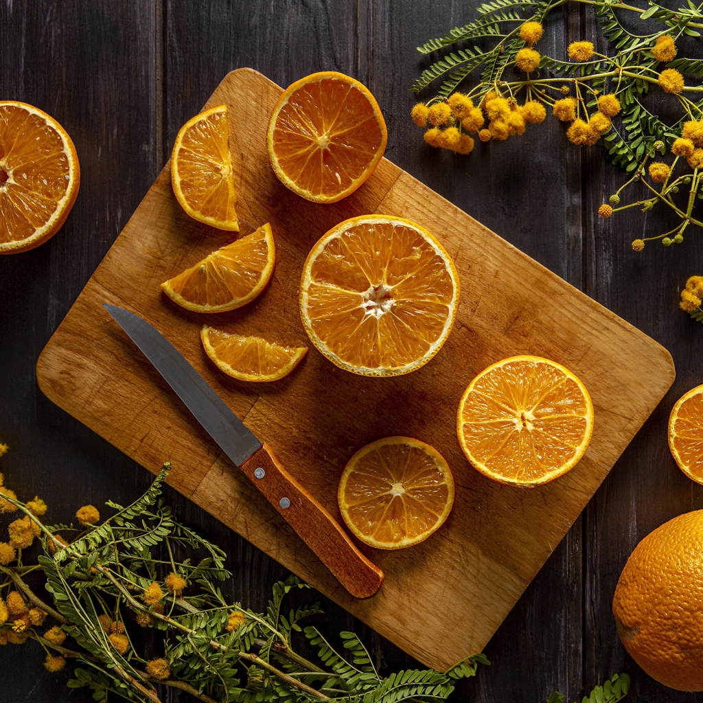 Нарезанный апельсин на доске на столе с цветами