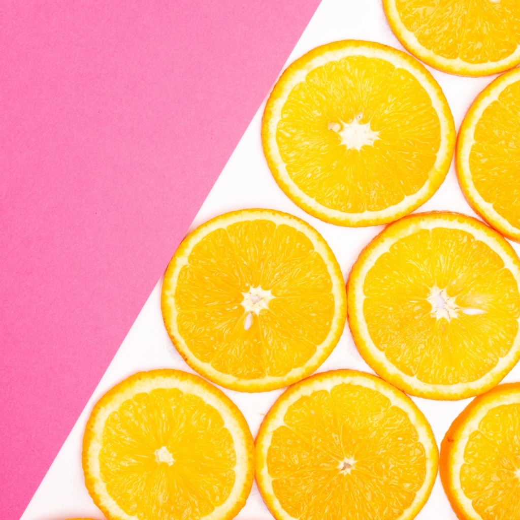 Нарезанный апельсин на бело-розовом фоне