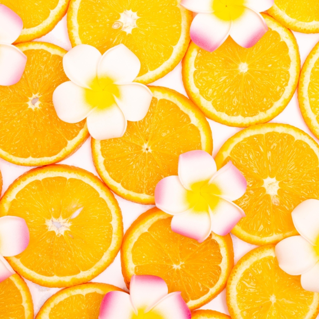 Нарезанный апельсин с цветами плюмерии для фона