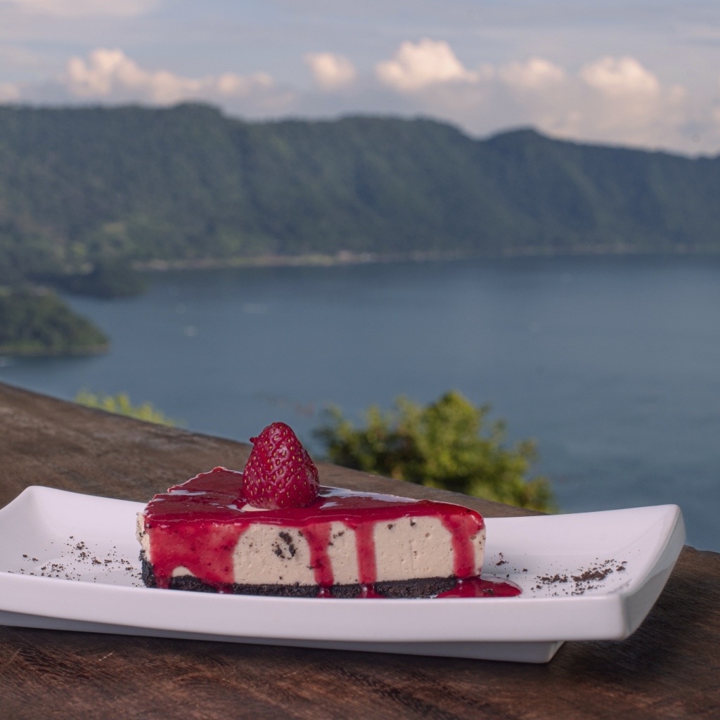 Кусок чизкейка с клубничным джемом на фоне моря