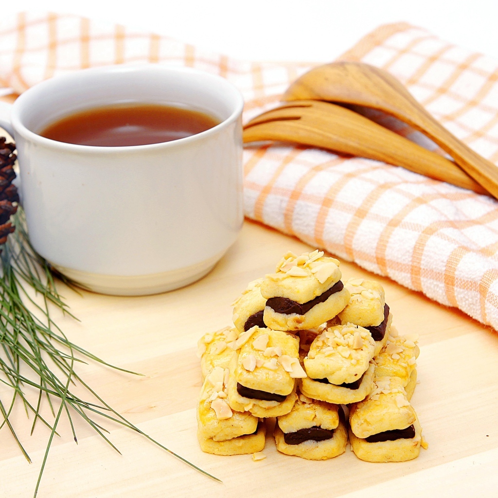 Печенье с чашкой чая и сосновой шишкой на столе