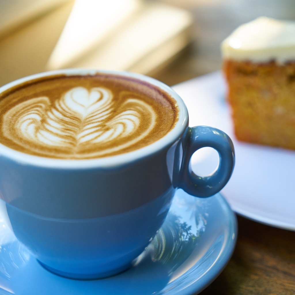 Чашка ароматного горячего кофе с рисунком на пене на столе на завтрак