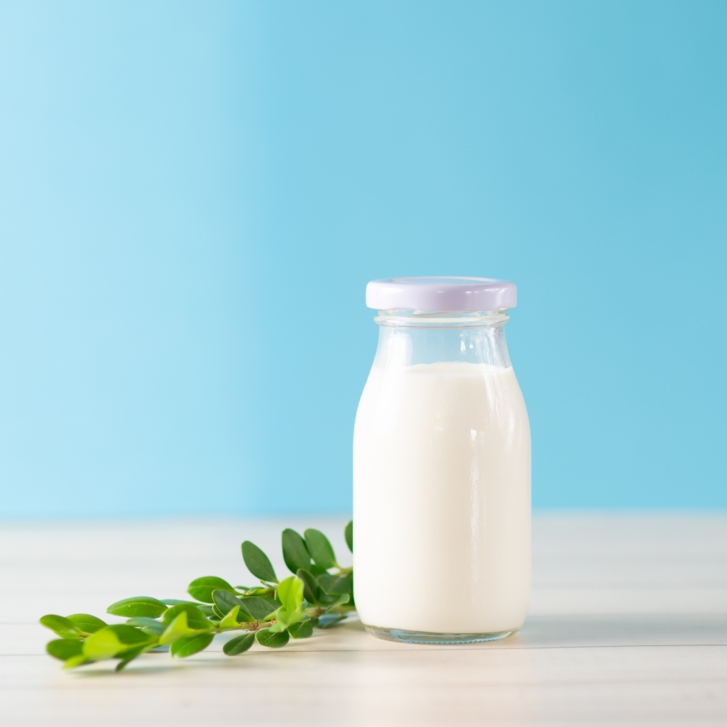 Бутылка молока с листьями на голубом фоне
