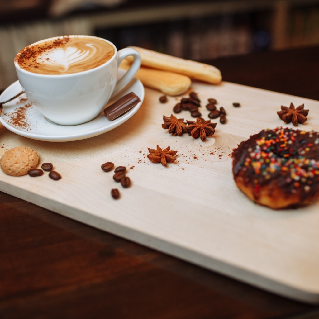 Чашка кофе на доске со специями и печеньем
