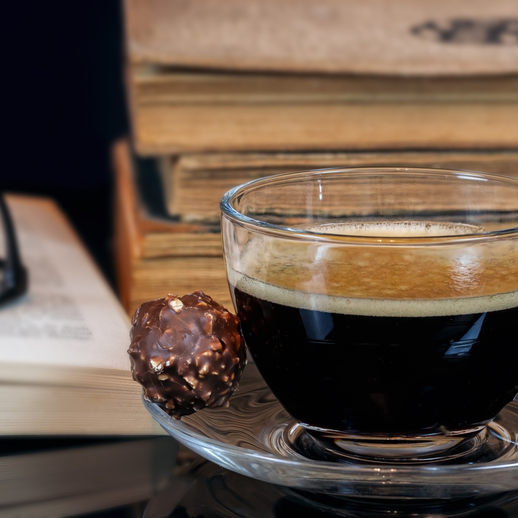 Чашка кофе на тарелке с шоколадной конфетой