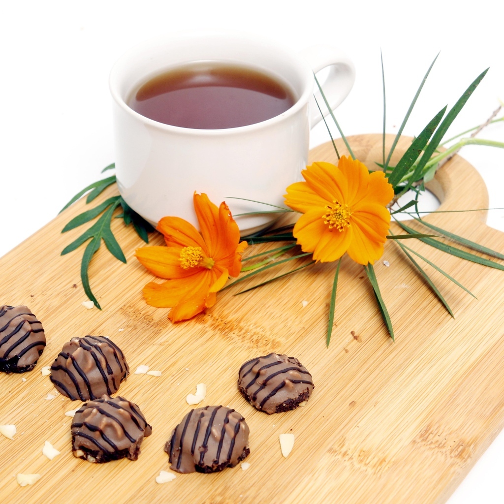 Чашка чая на деревянной доске с конфетами