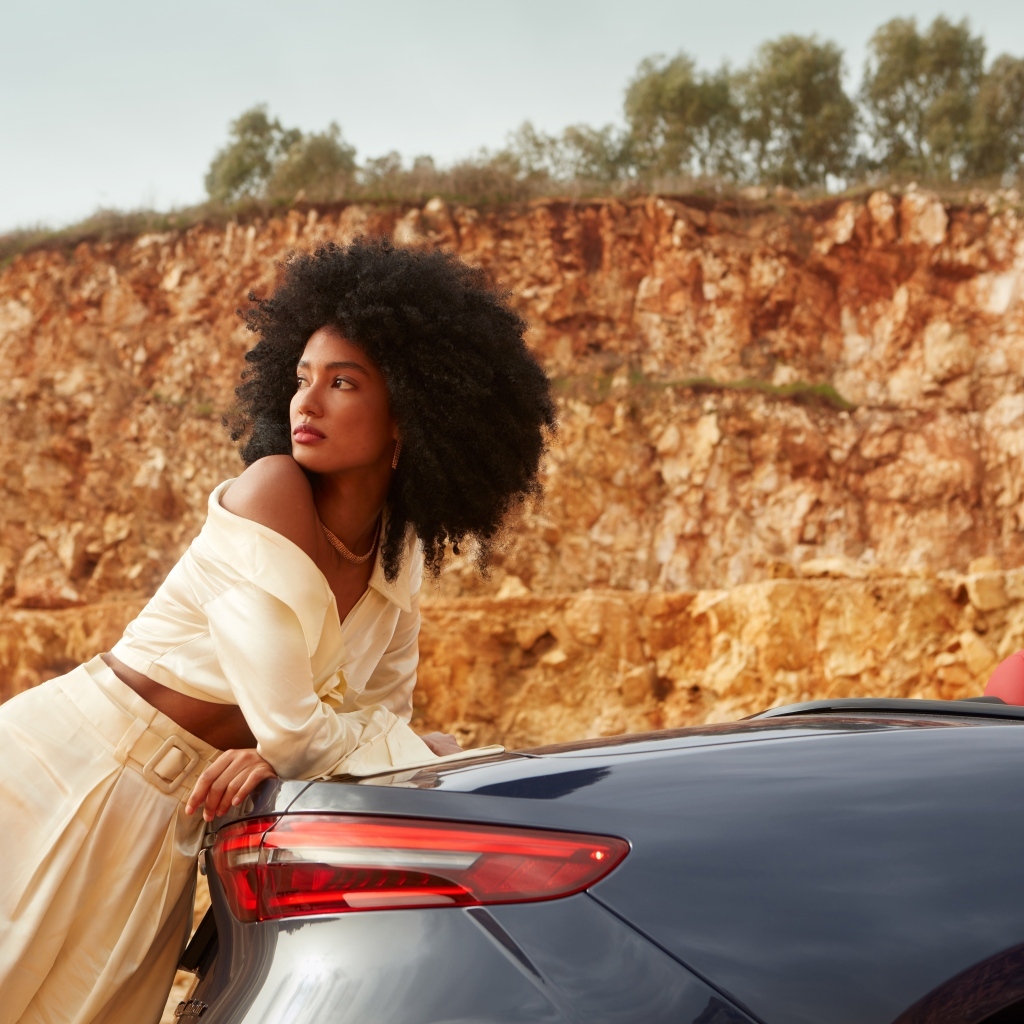 Темнокожая девушка стоит у автомобиля