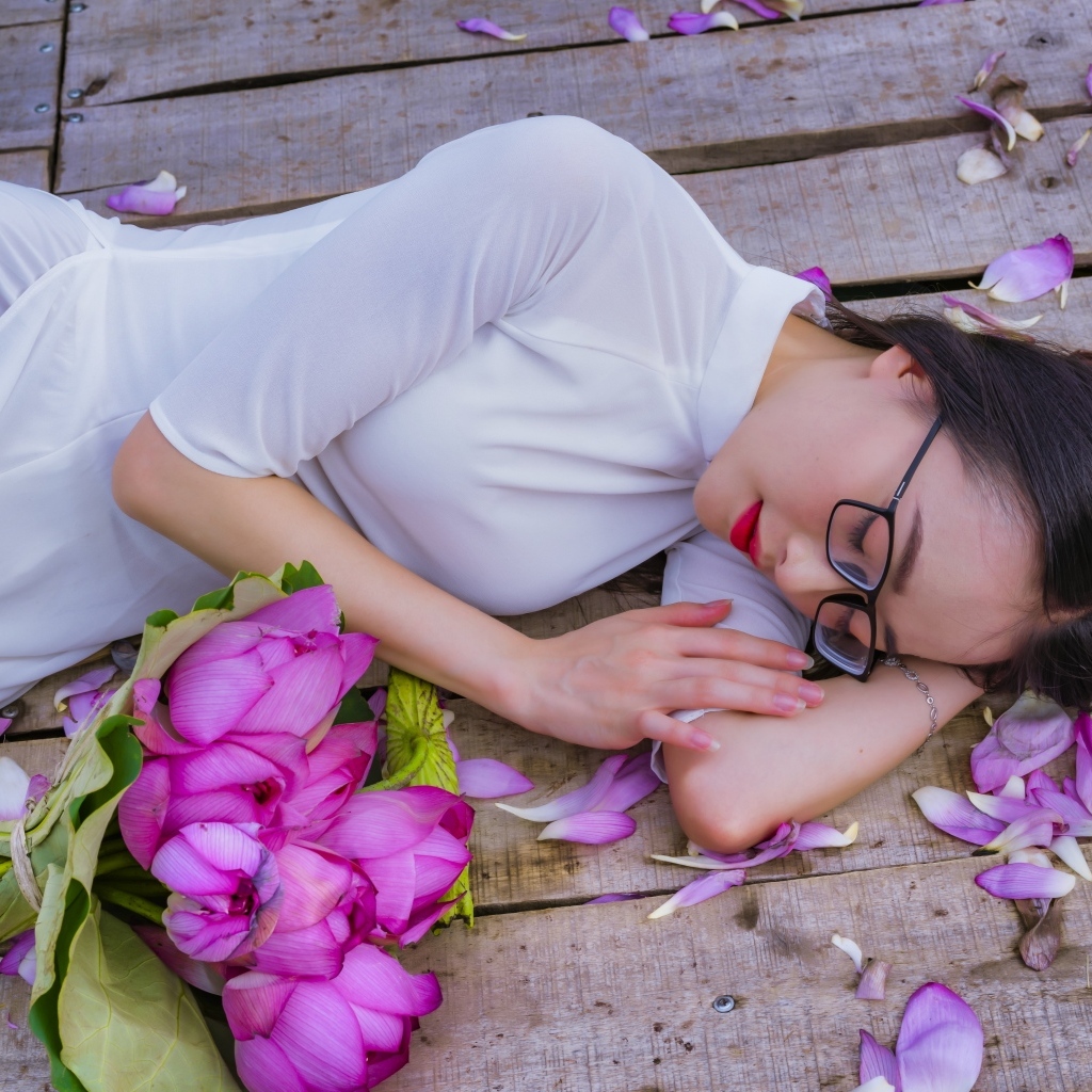 Девушка азиатка лежит с цветами лотоса
