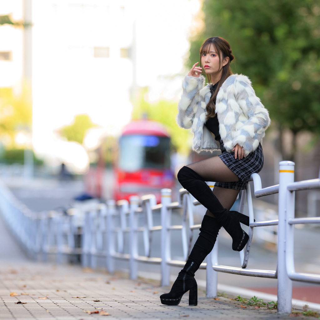 Азиатка в шубе стоит у забора