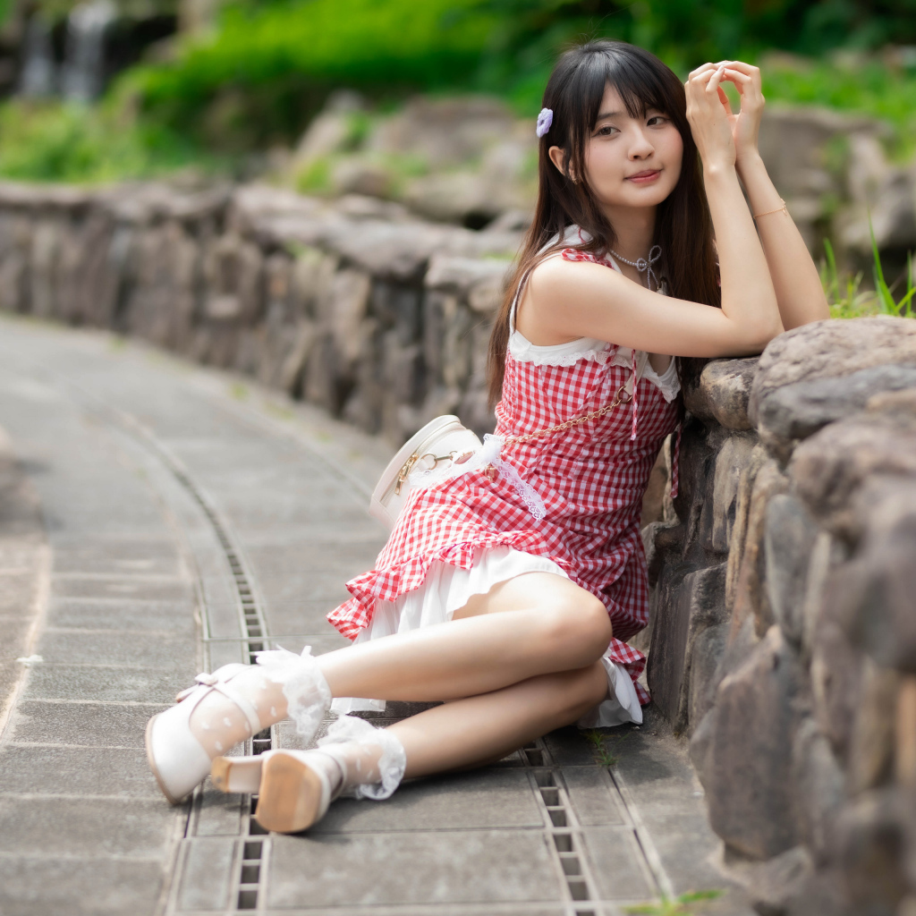 Азиатка сидит на земле в красном платье