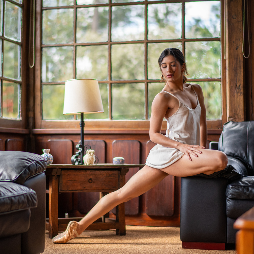 Девушка балерина делает шпагат в комнате