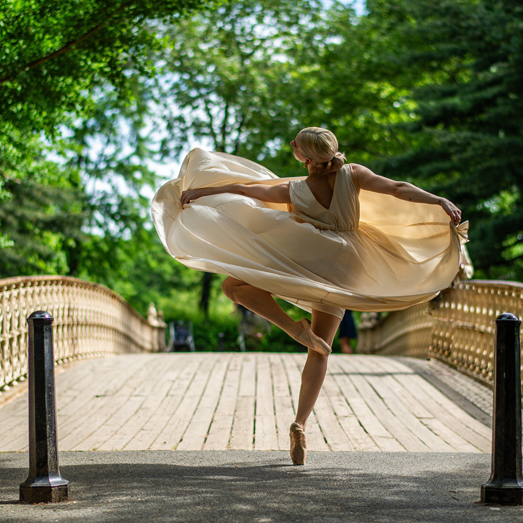 Девушка балерина в стойке на мосту