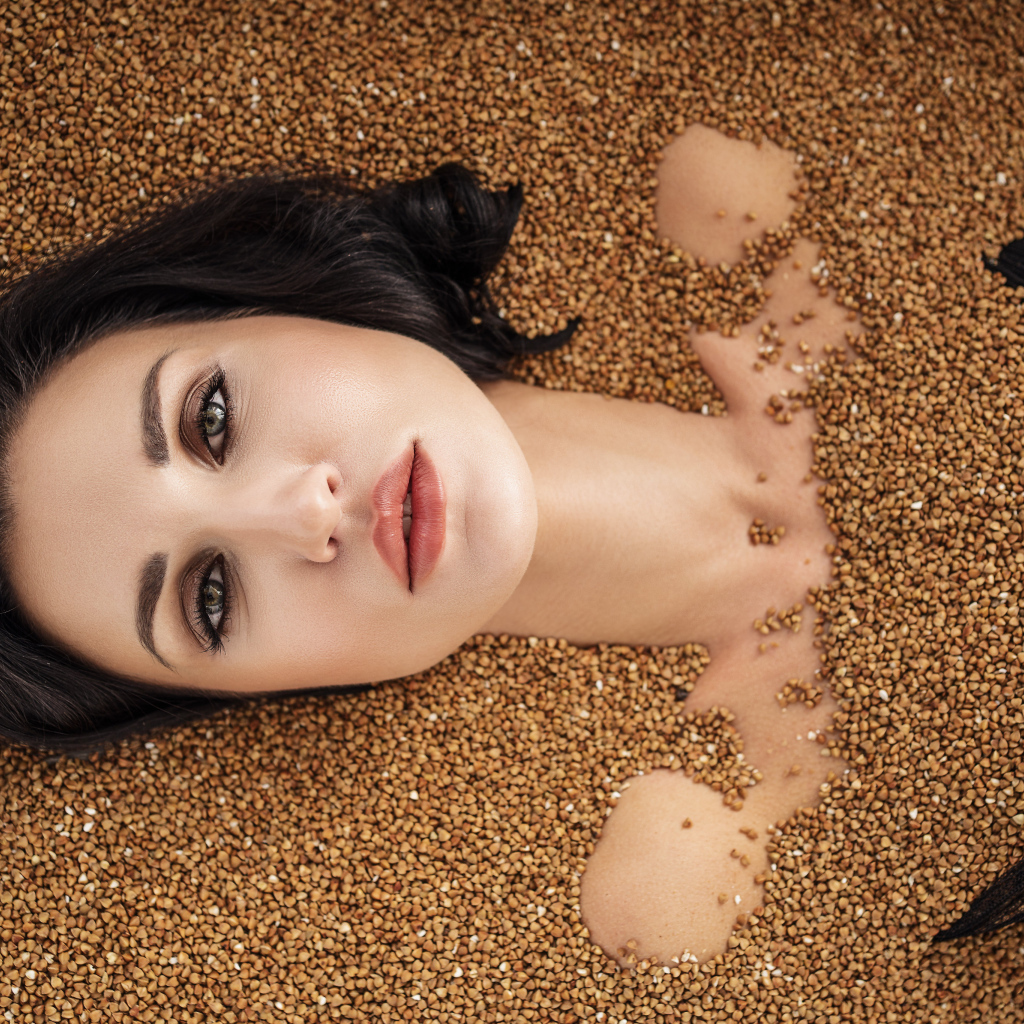Красивая девушка лежит в зернах гречки