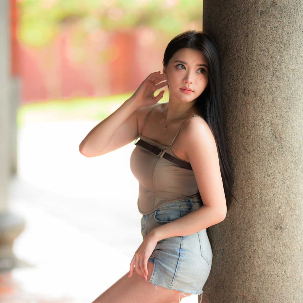 Милая длинноволосая азиатка стоит у колонны