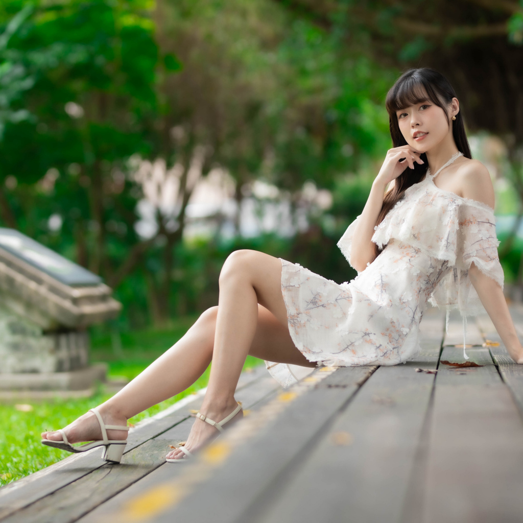 Симпатичная молодая азиатка сидит на деревянном покрытии