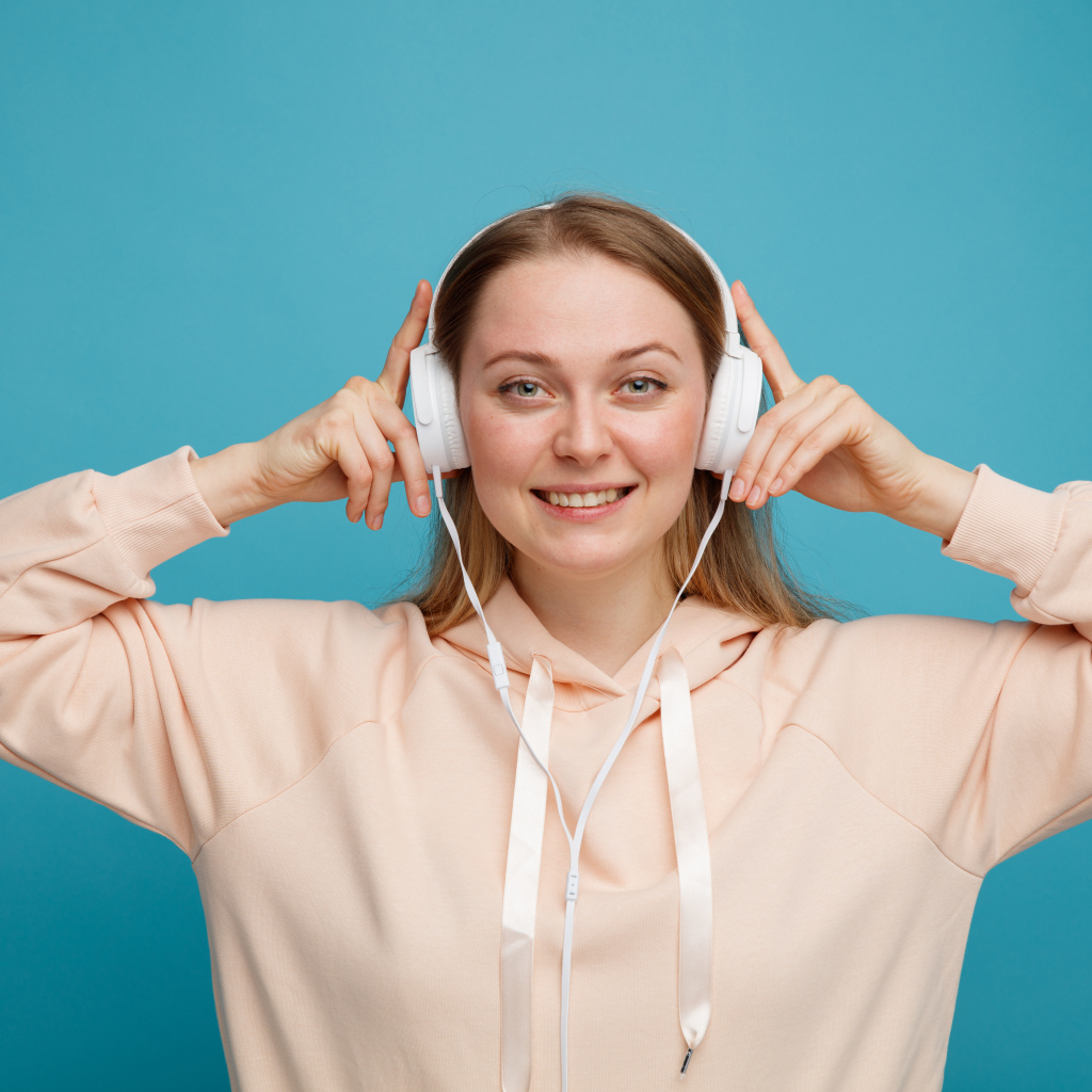 Улыбающаяся девушка в наушниках на голубом фоне