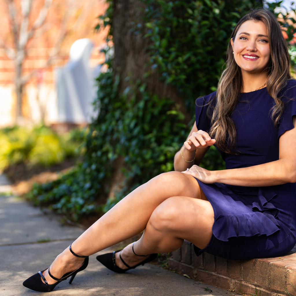 Улыбающаяся женщина в синем платье сидит на земле