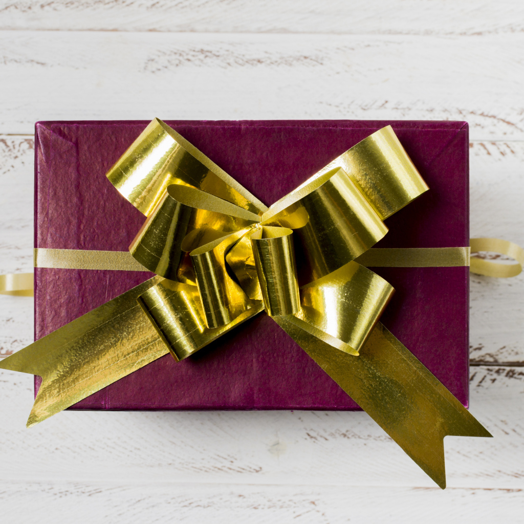 Красная коробка с подарком с золотым бантом на столе