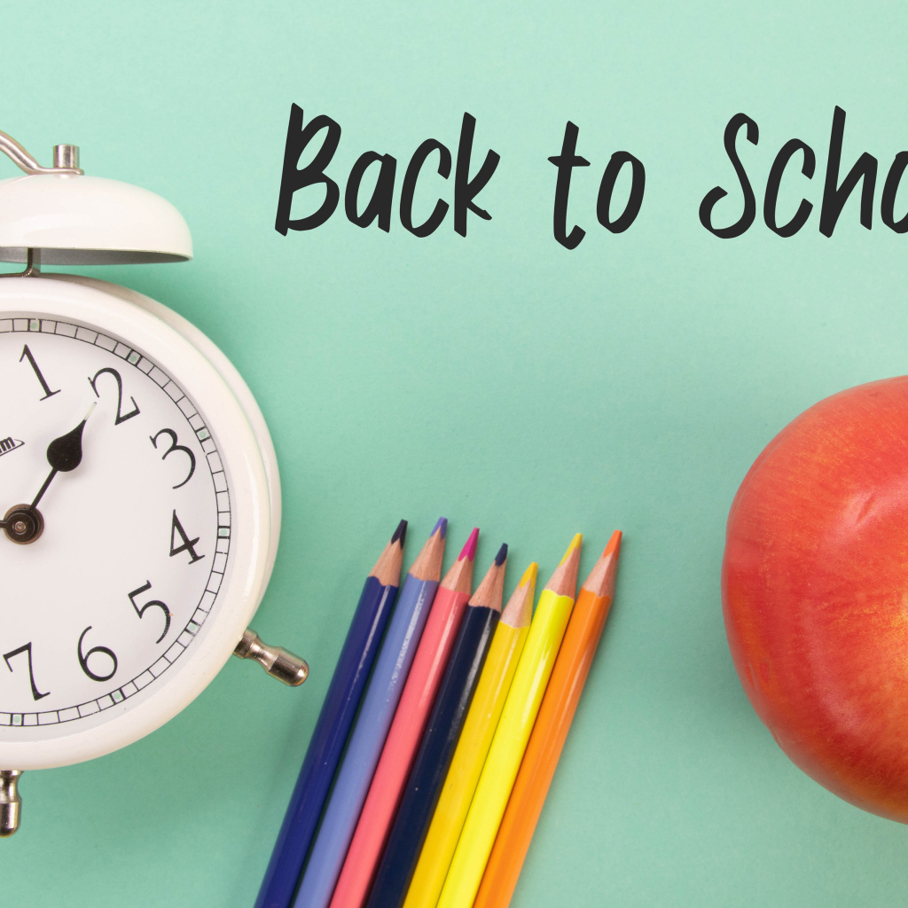 Будильник, карандаши и яблоко на фоне с надписью пора в школу