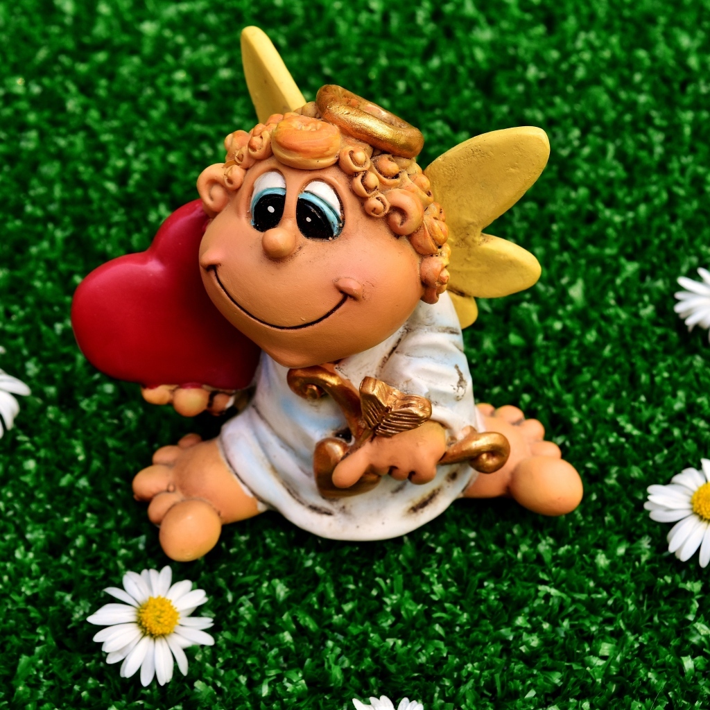 Статуэтка ангела на зеленой траве с белыми ромашками