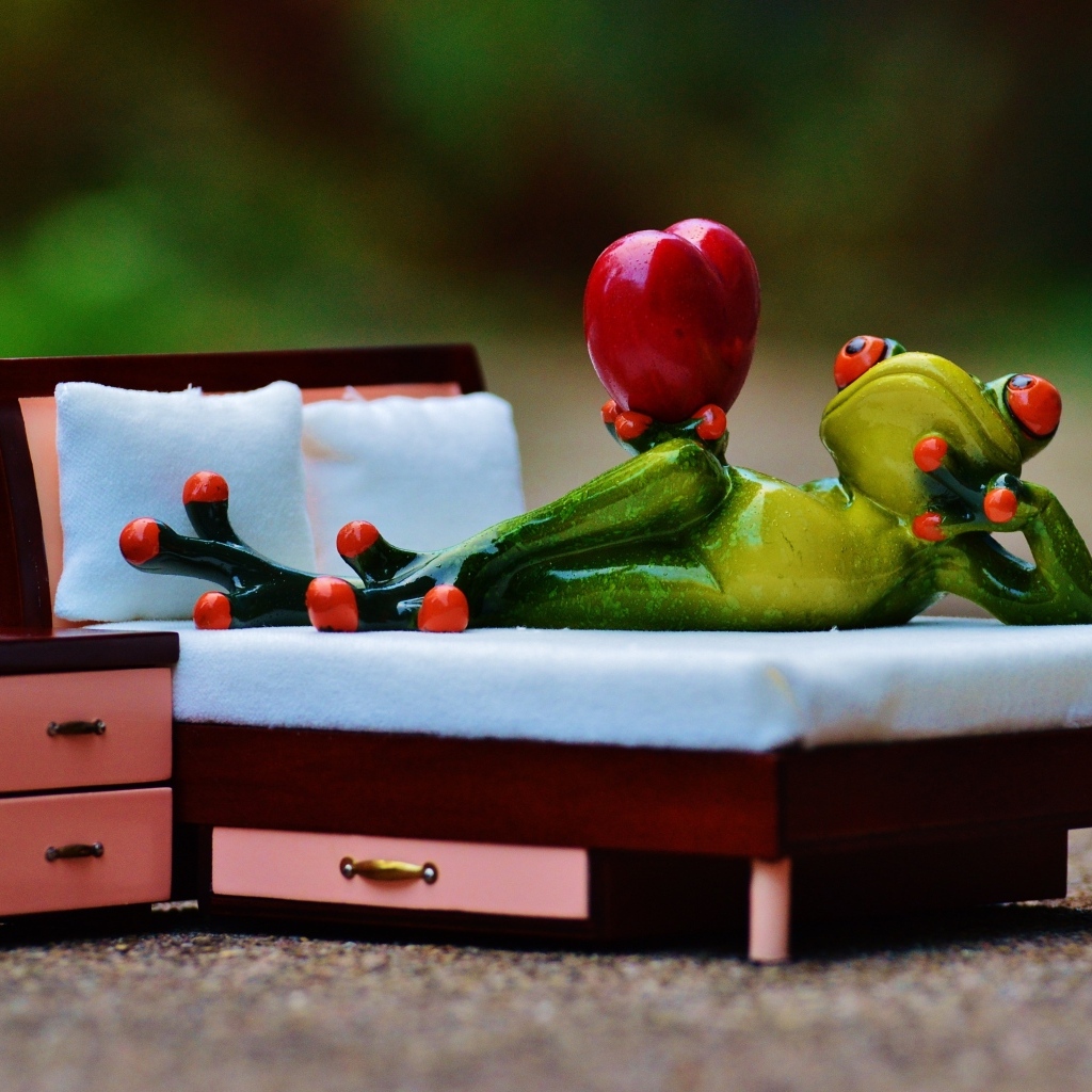 Фигурка зеленая лягушка с красным сердцем на кровати