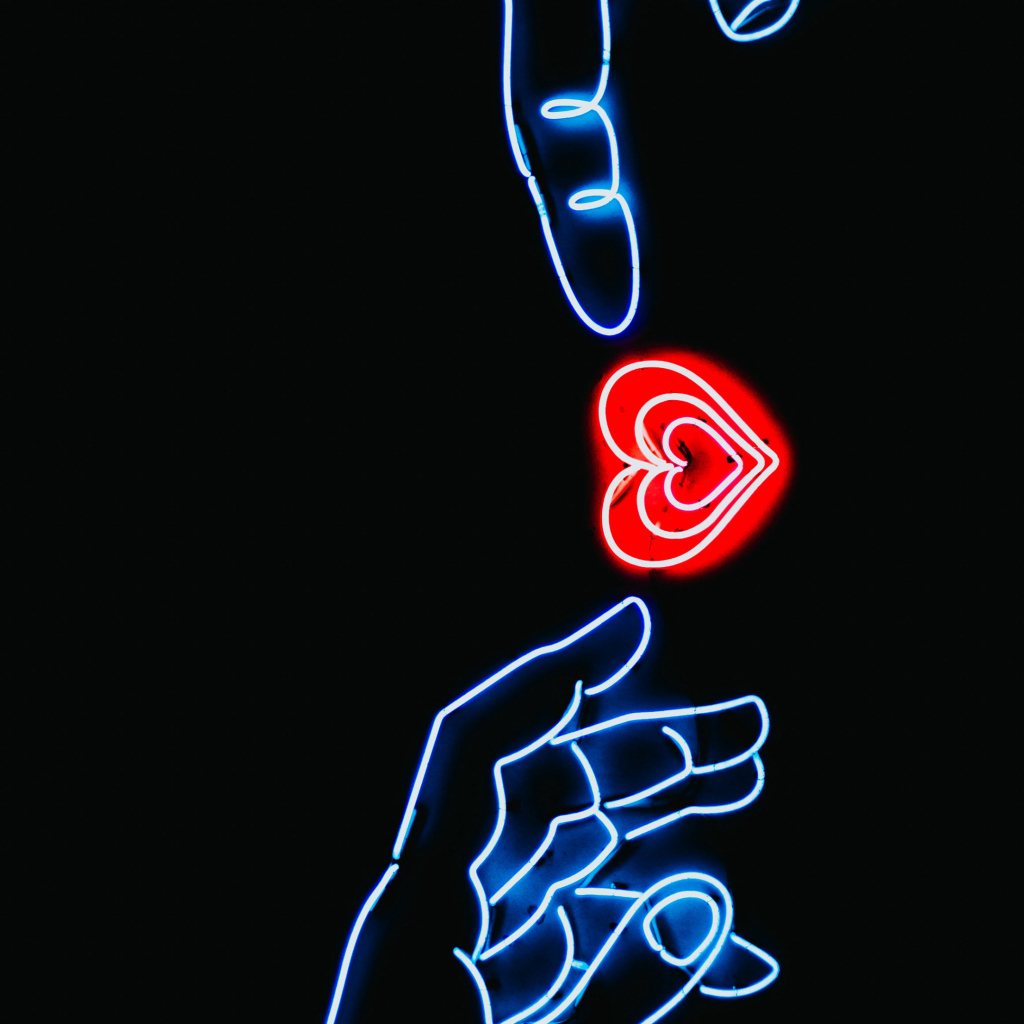 Неоновое красное сердце с руками на черном фоне