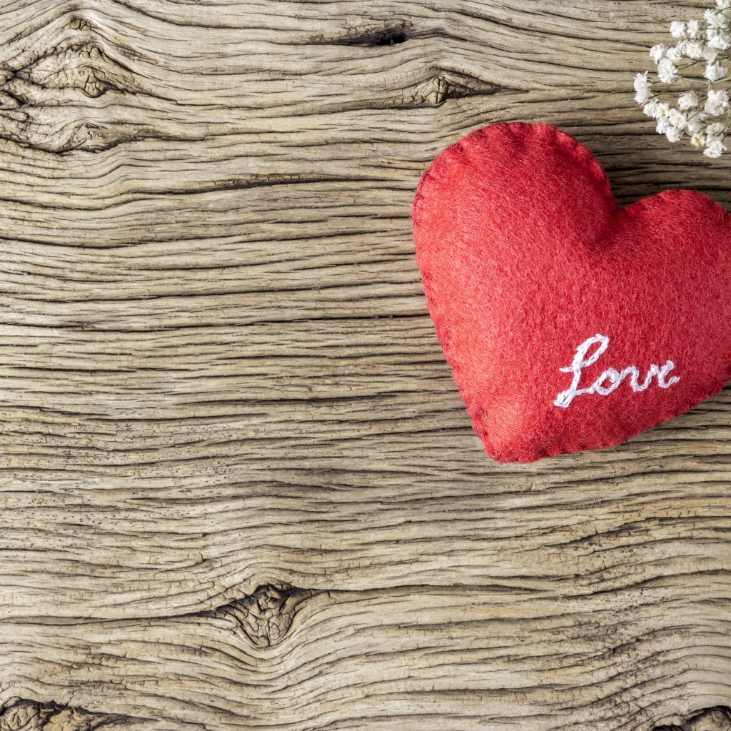 Красное тканевое сердце с цветами на деревянном столе