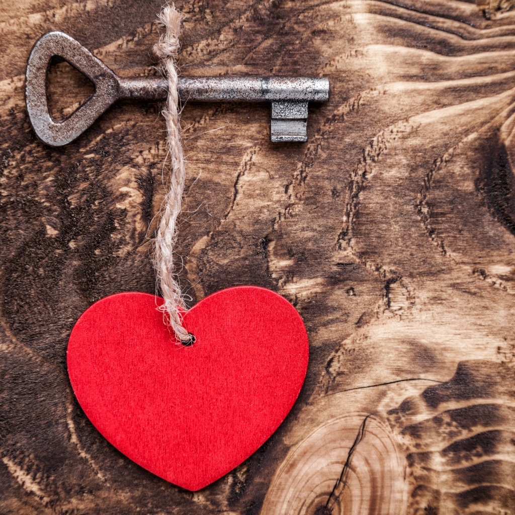 Красное сердце на нитке с ключом на деревянном фоне