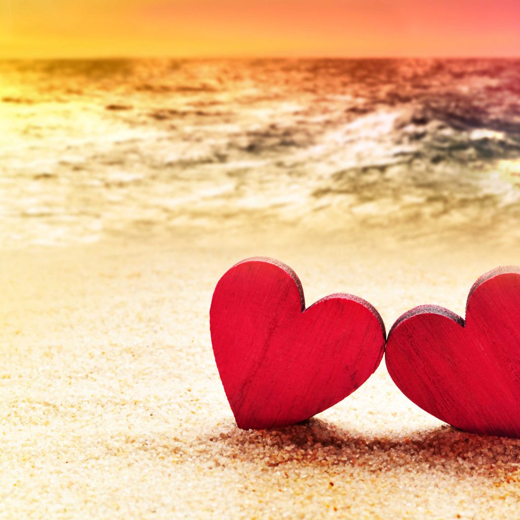 Два красных сердечка на песке на пляже