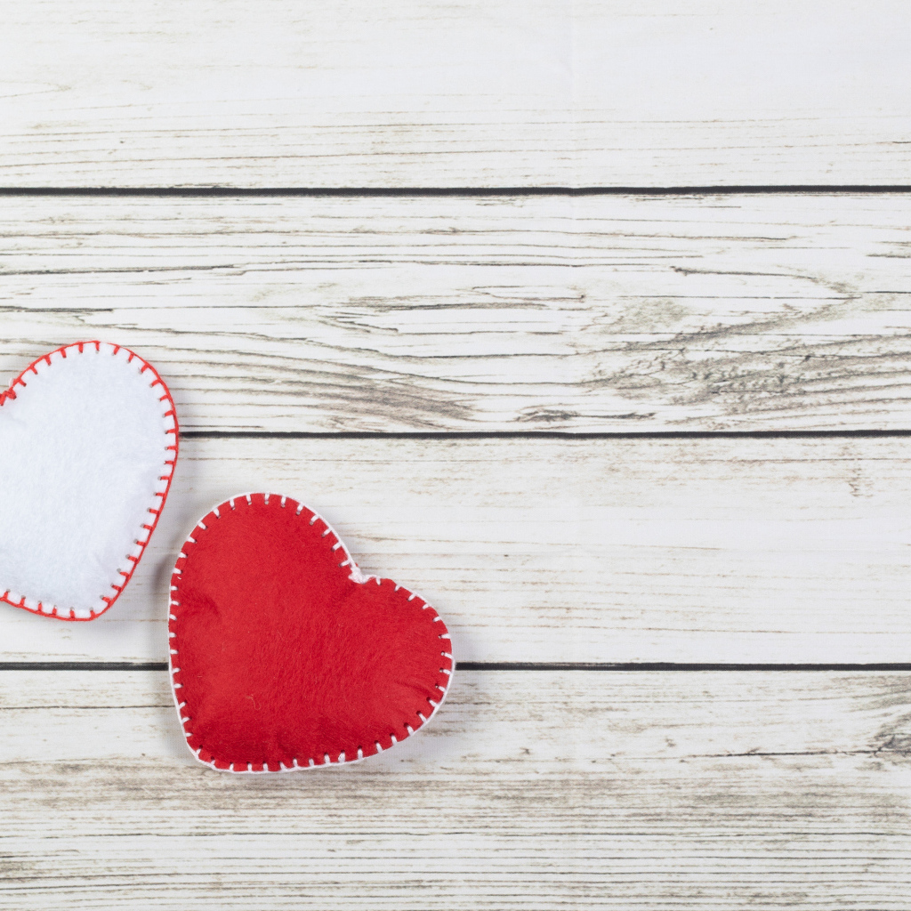 Белое и красное сшитое сердце на деревянном фоне