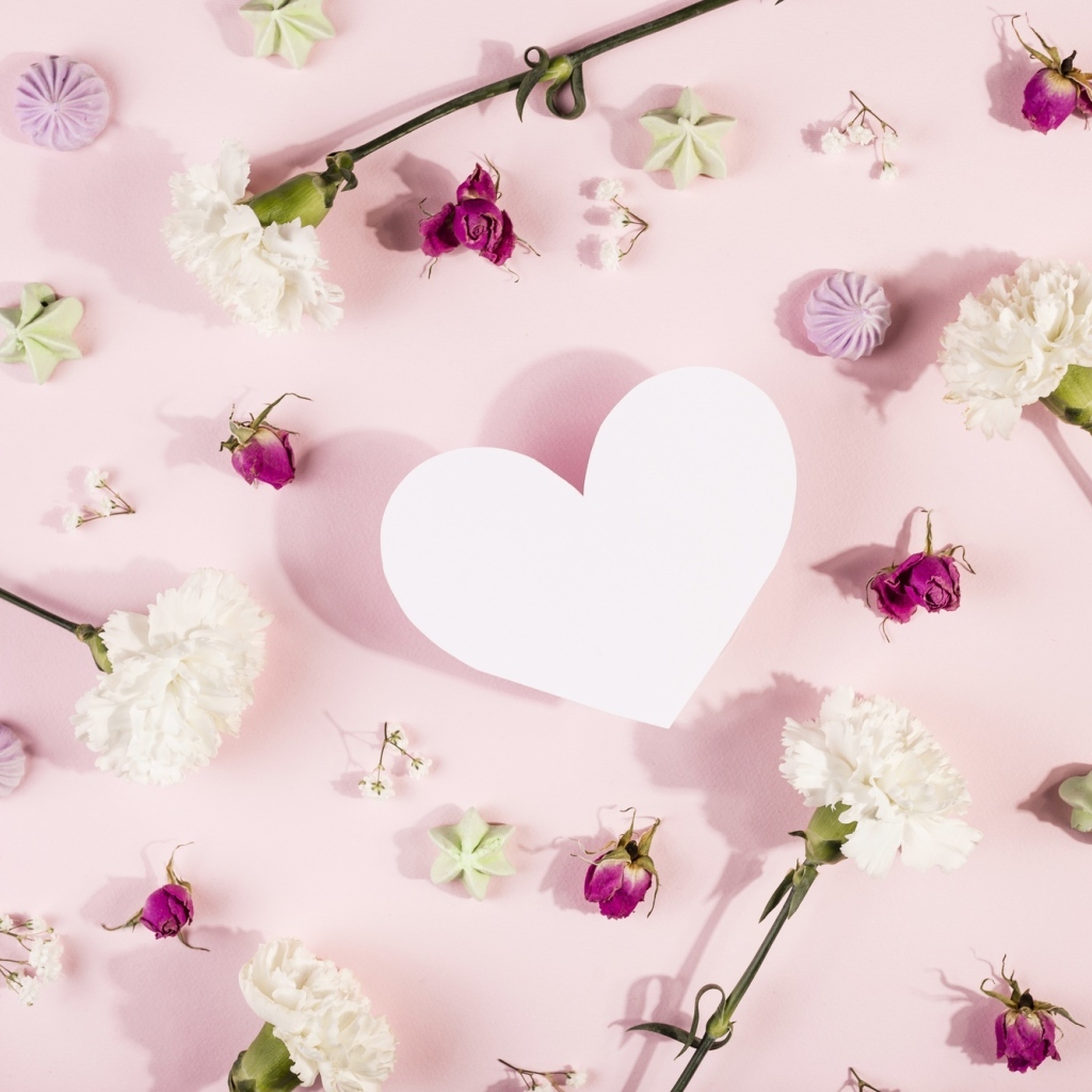 Белое бумажное сердце на розовом фоне с цветами