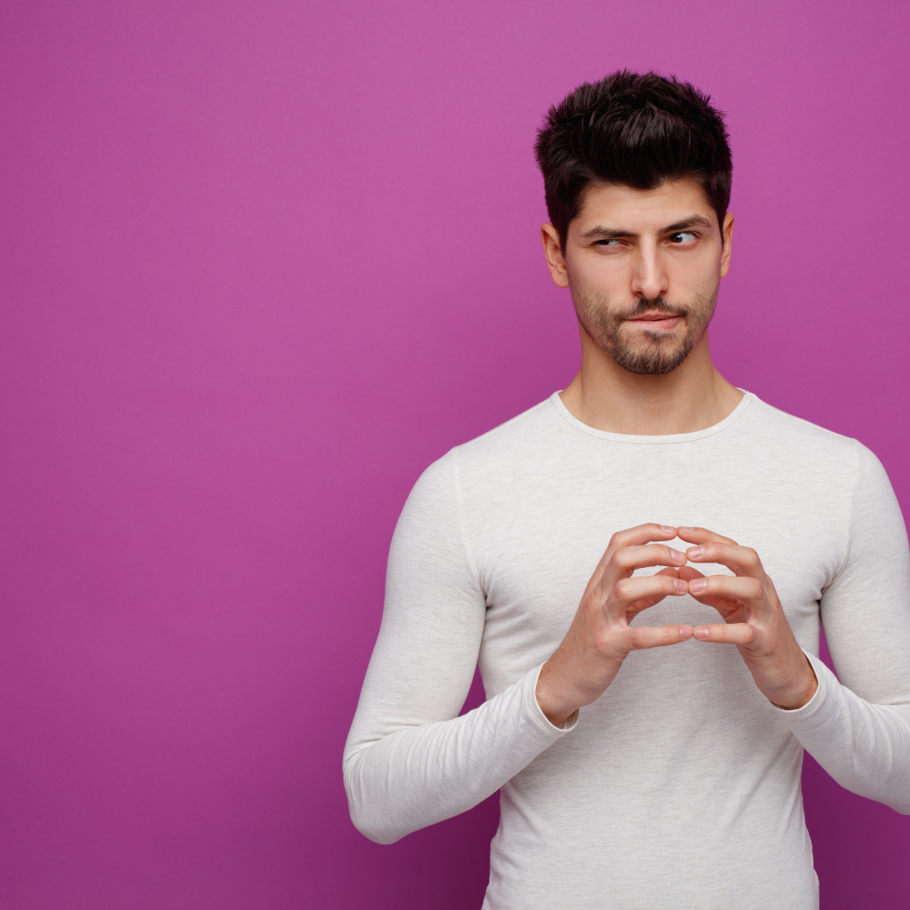 Хитрый мужчина в белом свитере на сиреневом фоне