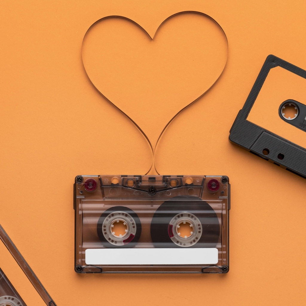 Кассеты и сердце из ленты на оранжевом фоне