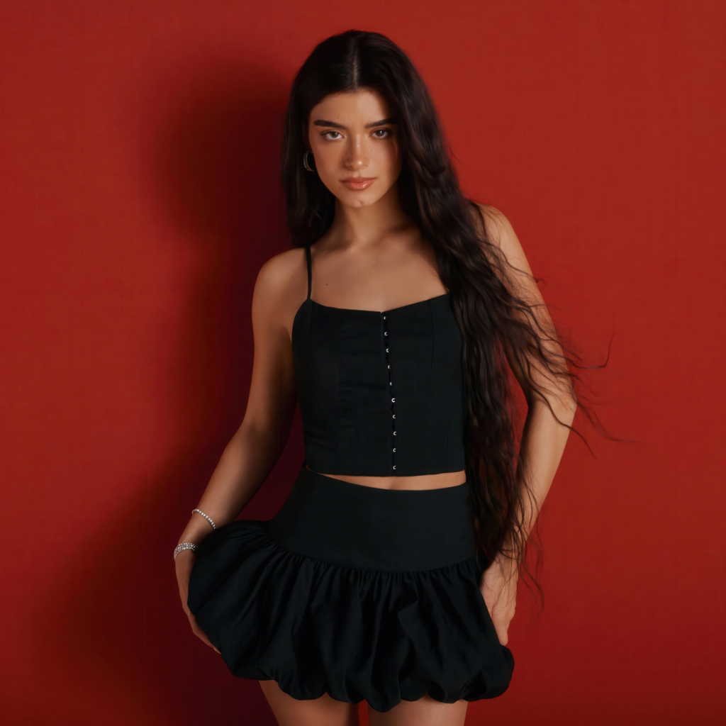 Популярная девушка Дикси Дамелио в черном костюме на красном фоне