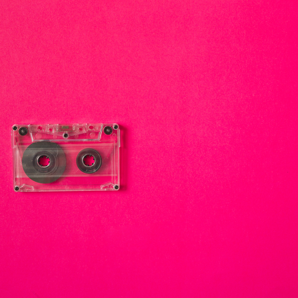 Маленькая магнитофонная кассета на розовом фоне