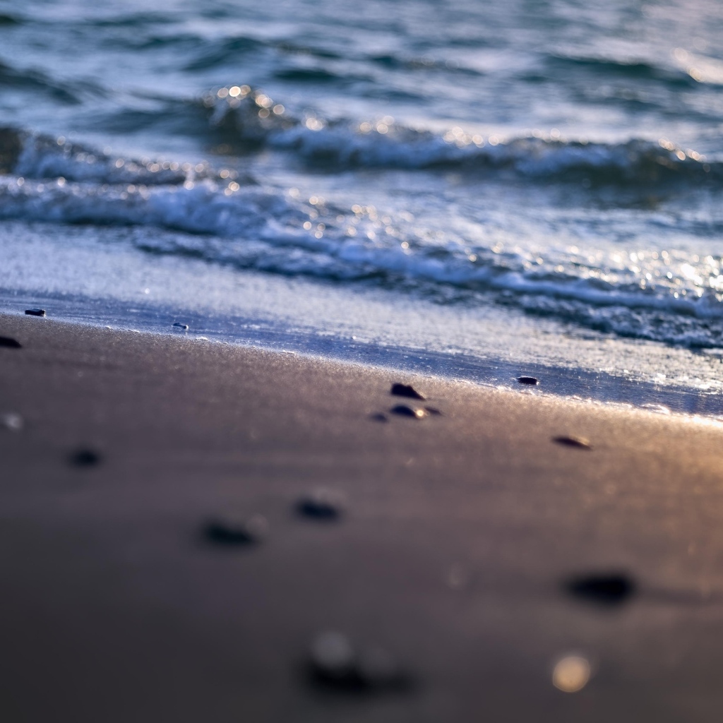 Мокрый морской песок омывает вода