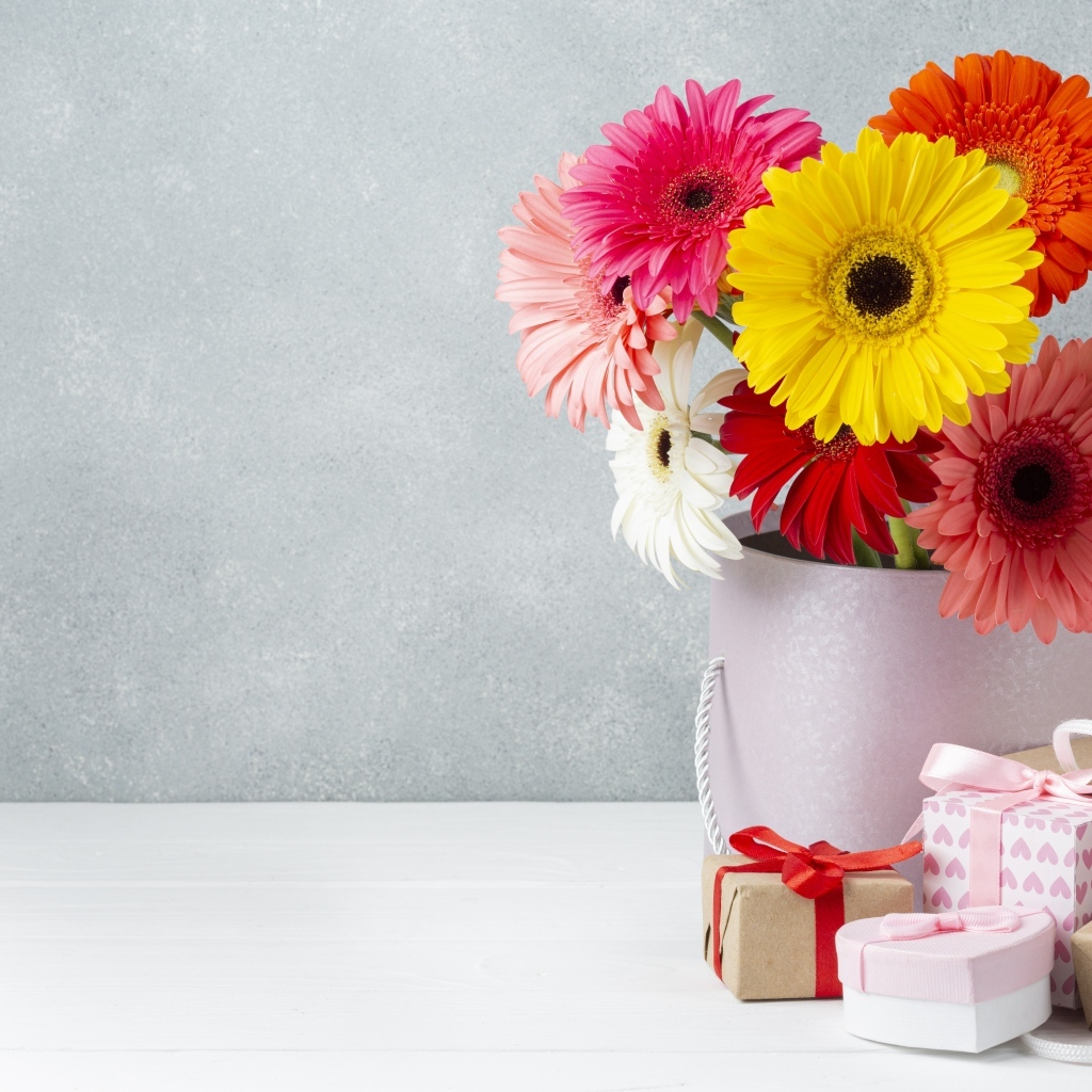 Букет разноцветных цветов герберы на столе с подарками