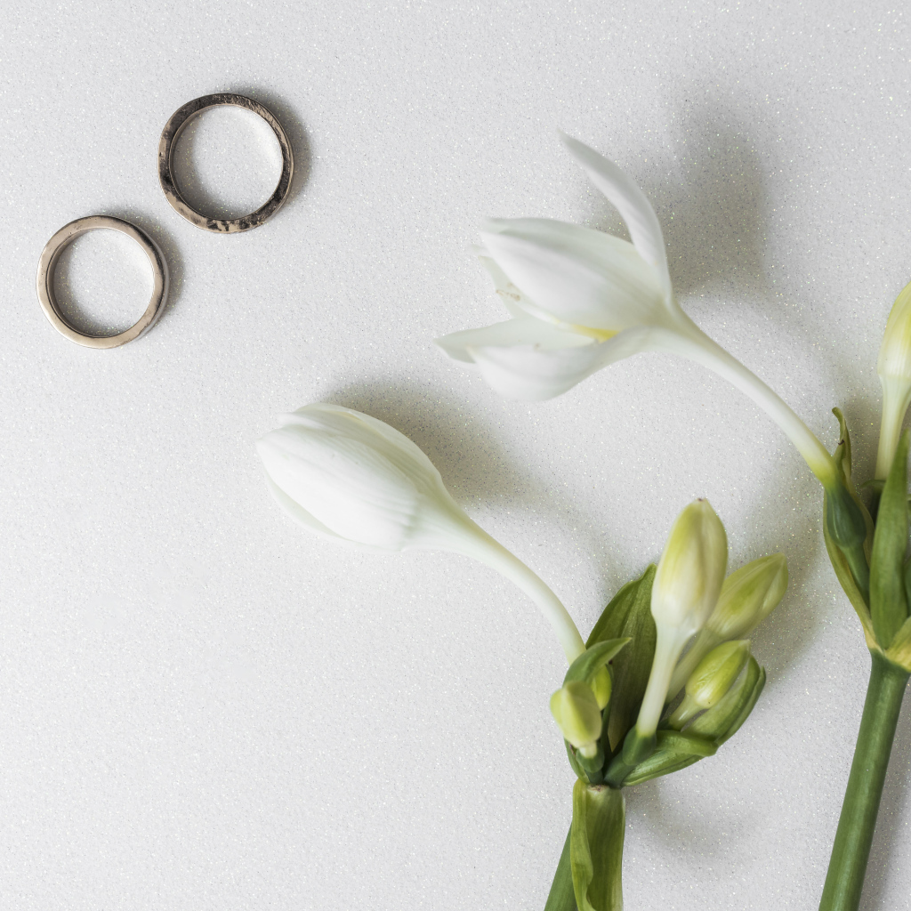 Два оручальных кольца с цветами на сером фоне