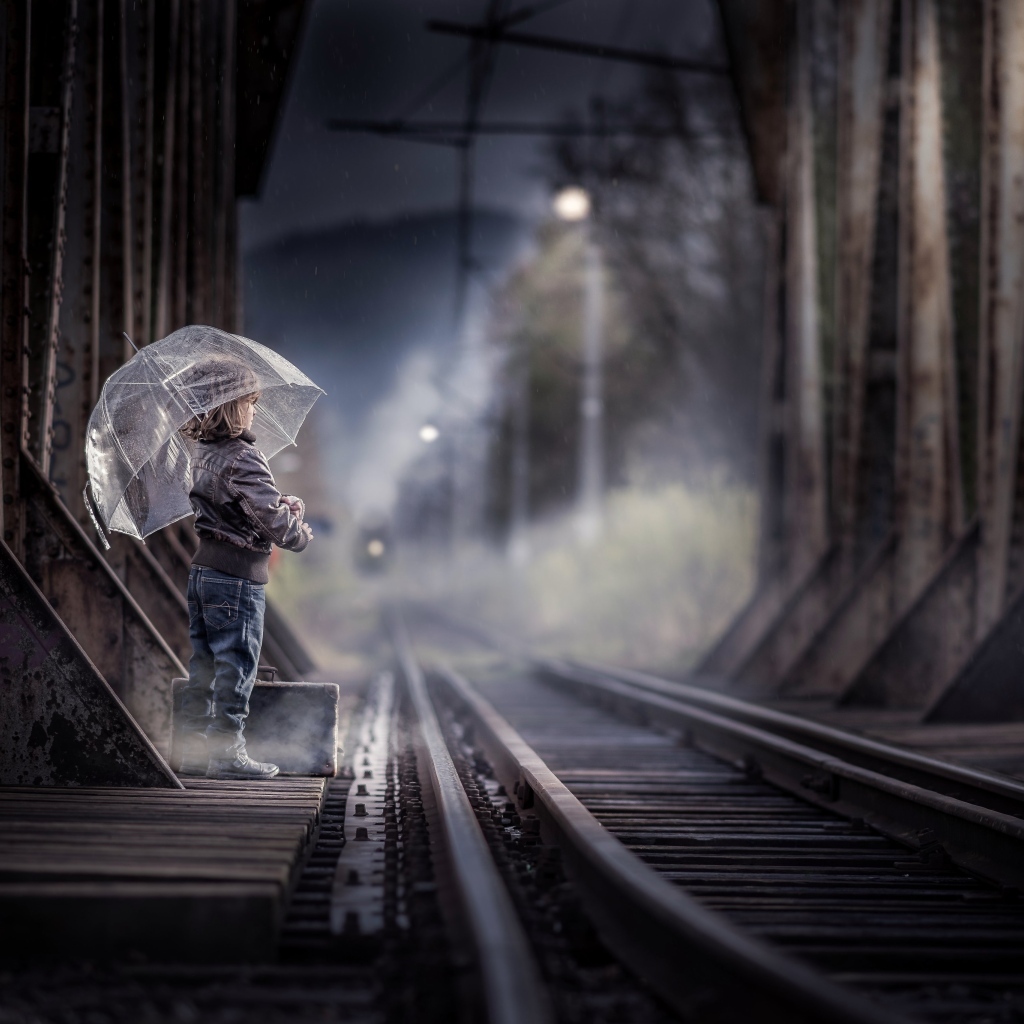 Ребенок под зонтом у железной дороги