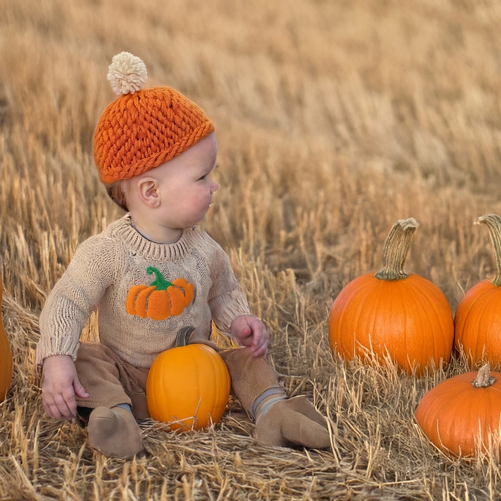 Маленький ребенок сидит на поле с тыквами